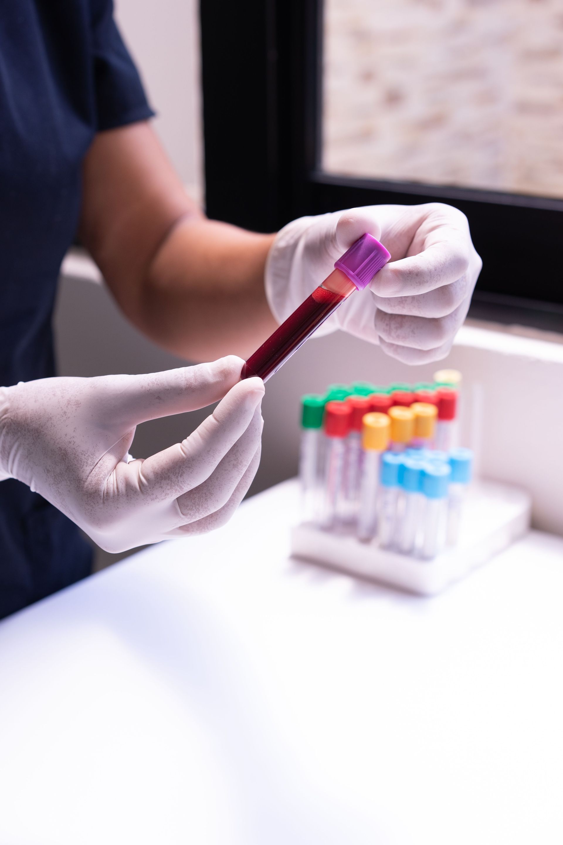 A healthcare worker examines a blood sample in test tubes, emphasizing medical precision and care.
