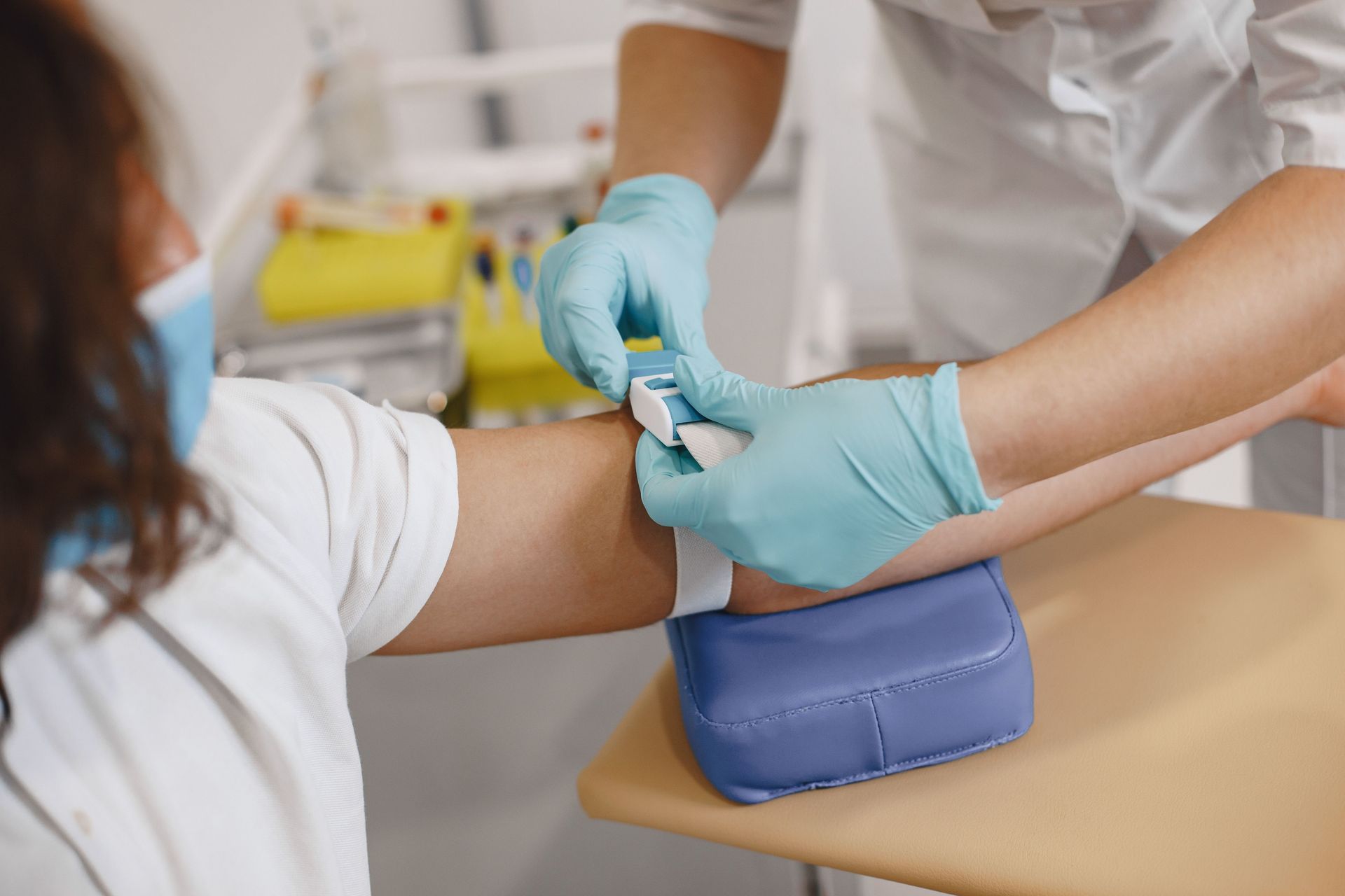 Close-up of a healthcare worker preparing a patient's arm for a blood draw in a clinic setting.